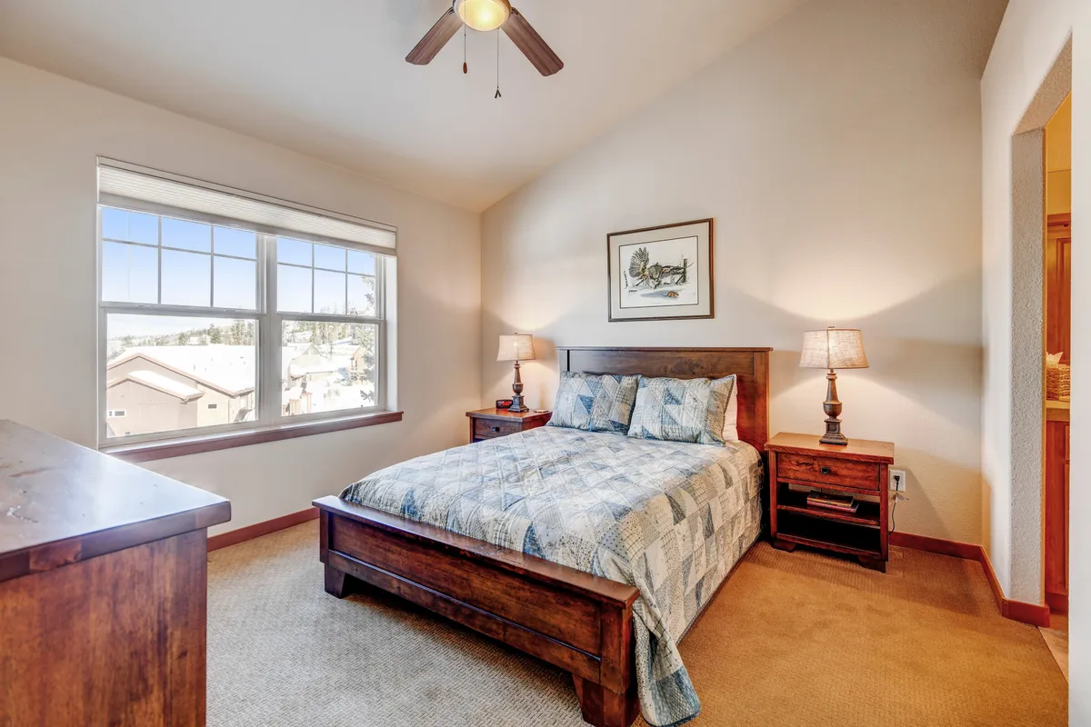 This image features a serene bedroom with a cozy bed adorned with a quilt, flanked by nightstands with lamps and a window offering a peaceful view. The space exudes tranquility and comfort, emphasizing the inviting nature of the accommodation's private sleeping quarters.