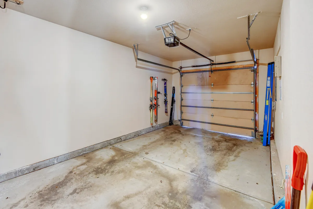 A garage interior with visible ski equipment, a garage door opener, and a clean concrete floor. The space is set up for storing sports gear and preparing for outdoor activities, highlighting the home's readiness for adventure.